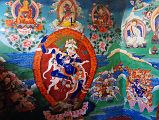 33 Paintings Outside Cave Of The Female Yak Horns Dirapuk Gompa Lion-Faced Goddess Dakini Simhamukha Senge Dongma, Padmasambhava Guru Rinpoche, Milarepa, Marpa, Shangpa Karpo, Shri Devi Palden Lhamo At the back of the Dirapuk Gompa is the cave of the female yak horns. Murals surround the entrance including the lion-faced-goddess Dakini Simhamukha (Tib. Senge Dongma). The face is a white lion with three round orange eyes blazing fiercely with a gaping mouth, and hair flowing upward. The right hand holds upraised a curved knife to the sky, left a skullcup of blood to the heart, carrying a khatvanga staff tipped with a trident in the bend of the elbow supported against the shoulder. Above to the left is Buddha, then Chakrasamvara (Tib. Demchog) in yab-yum with Vajrayogini (Tib. Dorje Phagmo), Padmasambhava (Tib. Guru Rinpoche), Milarepa holding his hand to his ear, Milarepas teacher Marpa, At the lower left is the worldly protector Shangpa Karpo, white, with one face and two hands holding a lance in the right and a bowl of jewels in the left; riding a white horse. Im not sure who the figure is to the right of lion-faced goddess. He is white with one face and two hands holding upraised in the right a riding whip and in the left a spear with a red banner. The final figure to the lower right is Shri Devi (Tib. Palden Lhamo), dark blue in colour, riding side saddle on a white mule with a sword in her upper right, a skullcup in her lower right, and khatvanga in her first right hand and another staff in her far right hand. She has a sun and moon disc at her waist.